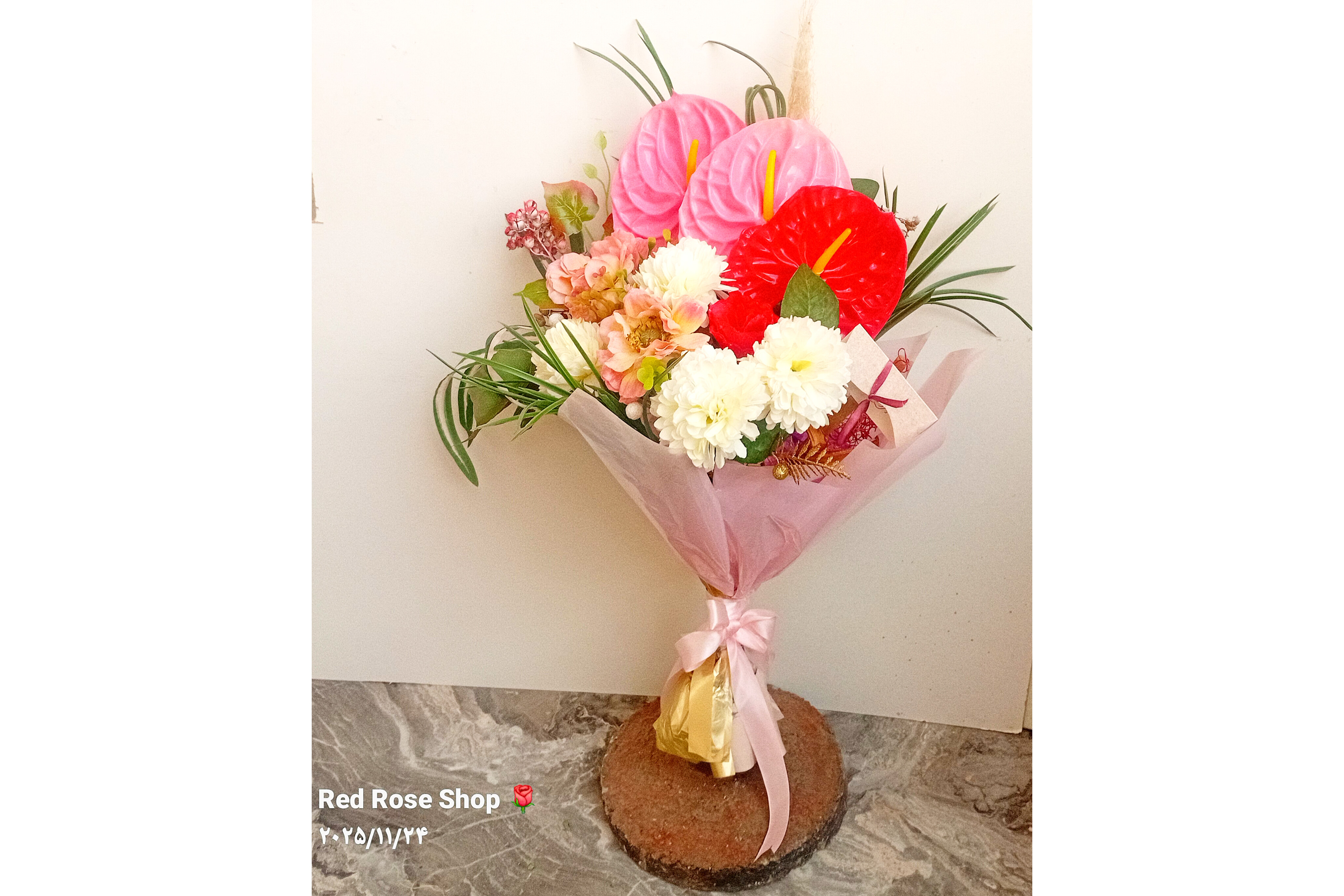 دسته_گل_مصنوعی_تبریک_انتوریوم_صورتی_داوودی_سفید_پیونی_صورتی_تزیین_کاغذ_روبان_صورتی